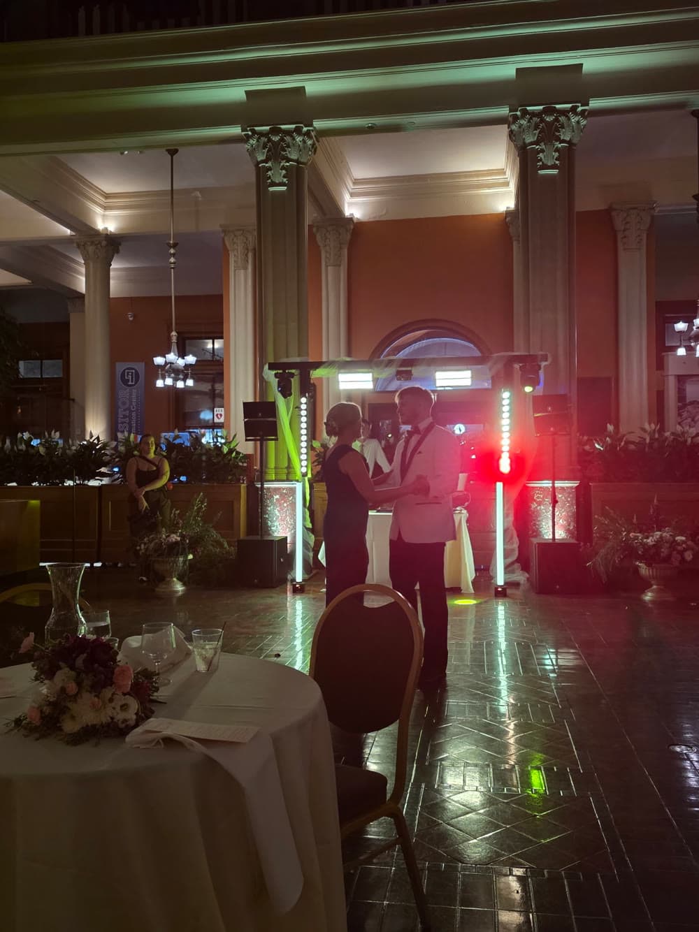 Couple dancing in a grand columned hall with red and green event lighting