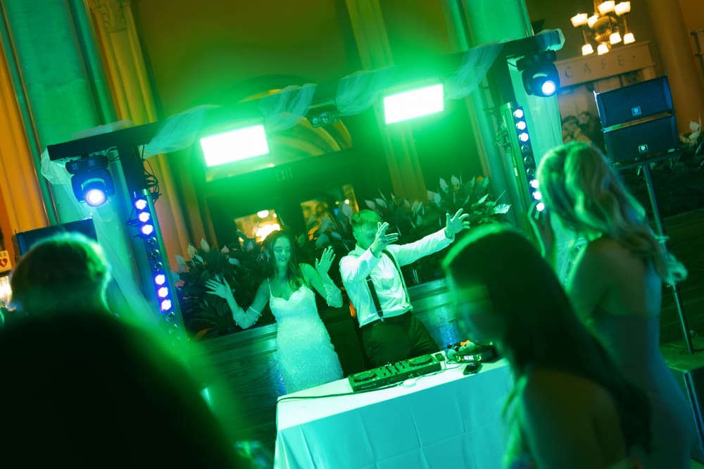 Couple celebrating behind the DJ booth under neon green production lights