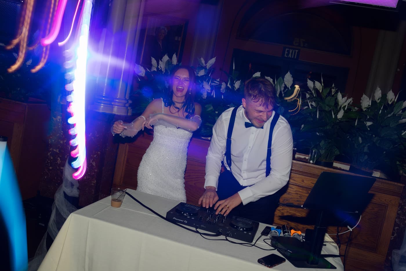 DJ and dancer celebrating behind the booth with blue and magenta light streaks