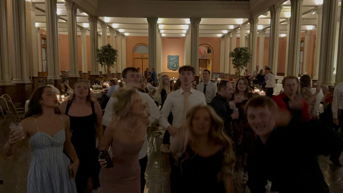 Friends singing and dancing in a columned event hall